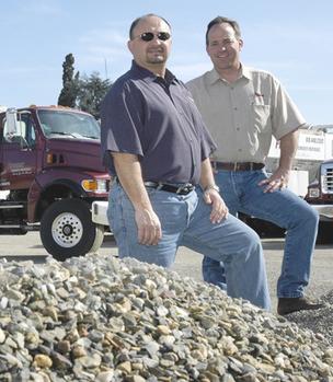 Owners Of Precision Concrete Materials Standing together Behind A Small Pile Of Rocks